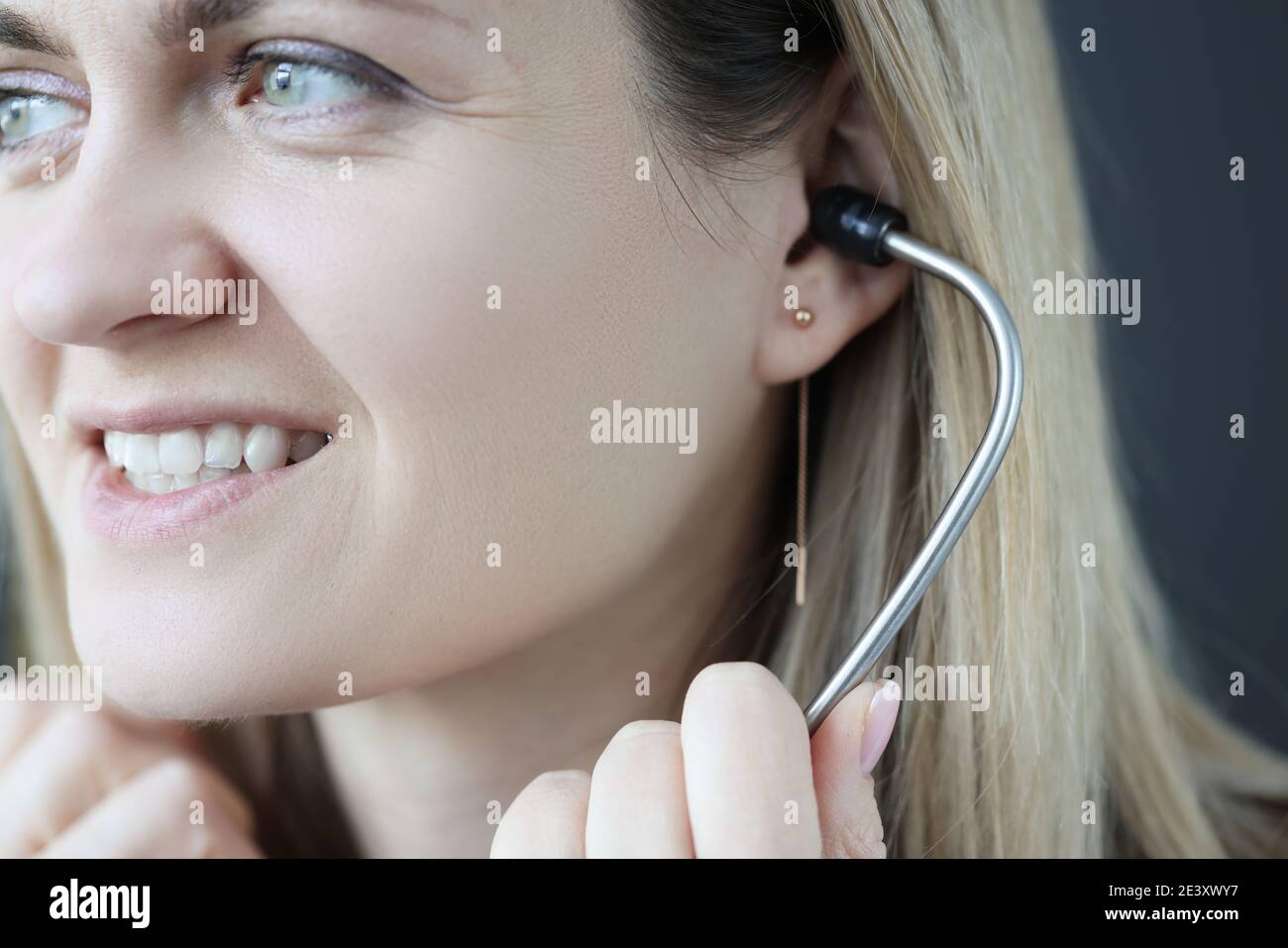 Doctor cardiologist inserting stethoscope into ears in clinic Stock Photo