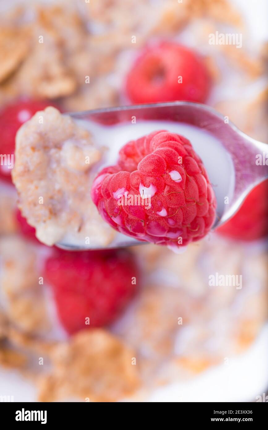 top view, close-up, a spoon with brown rice flakes, milk and fresh raspberries. Stock Photo