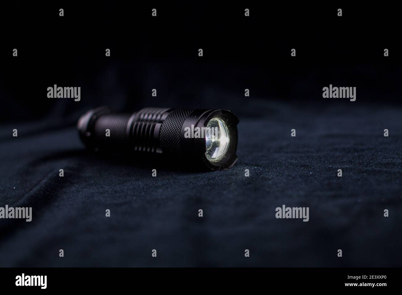a tactical flashlight on black background shines Stock Photo