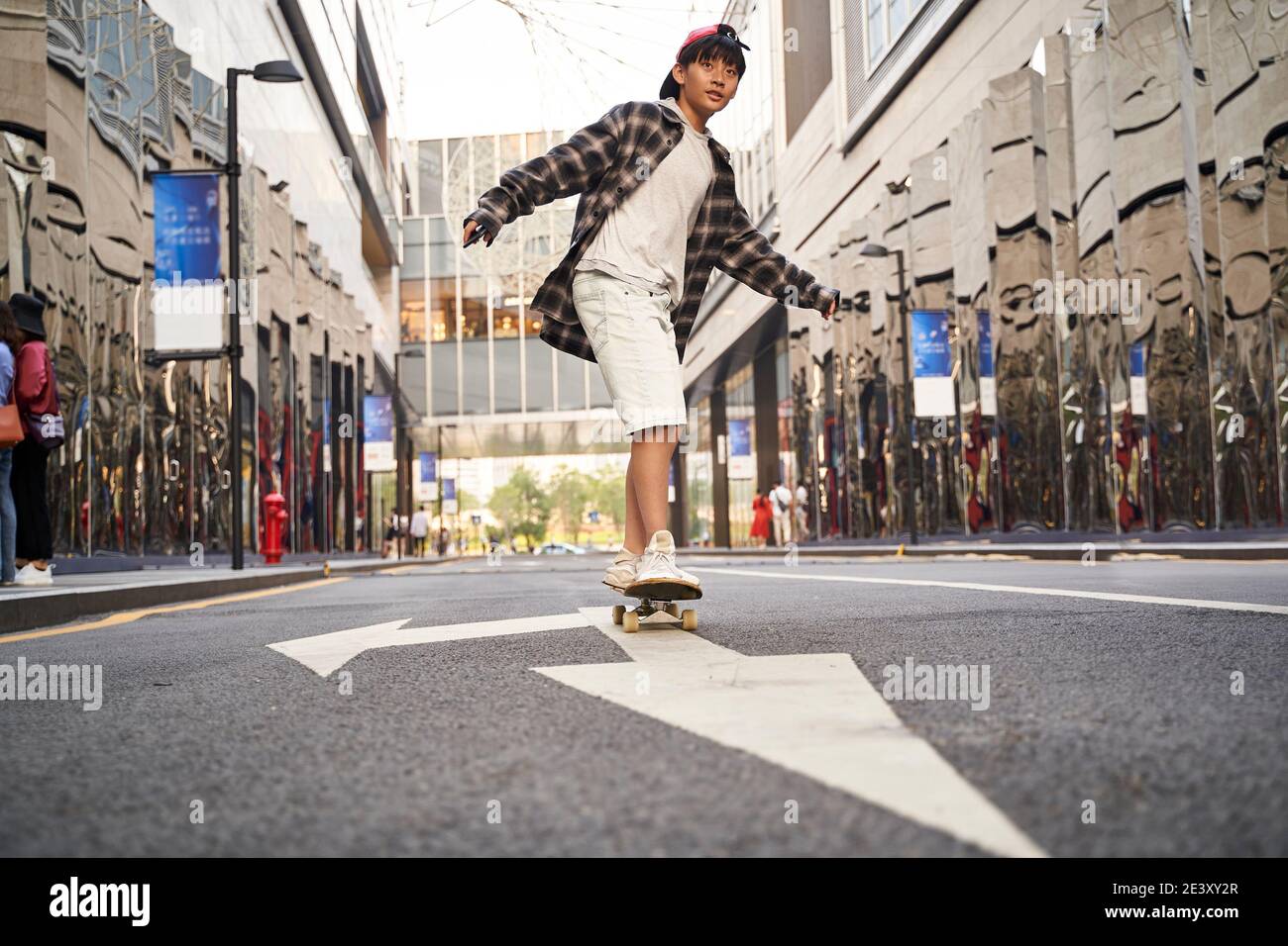 teenage asian child skateboarding outdoors in the street Stock Photo