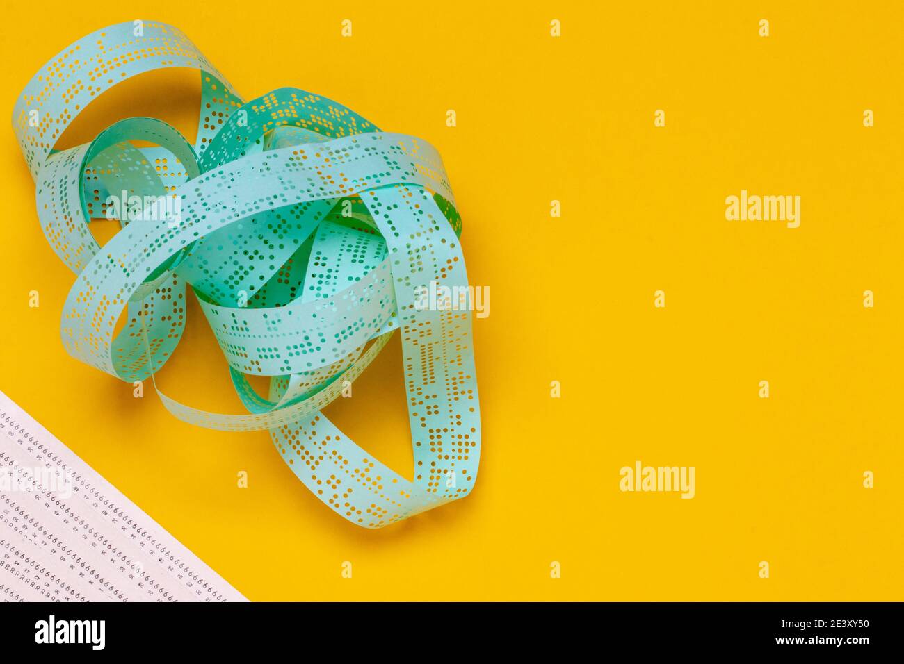 Storage media. Closeup of a vintage perforated punched tape and unused computer punch cards on a yellow background. Technology in last century for dat Stock Photo