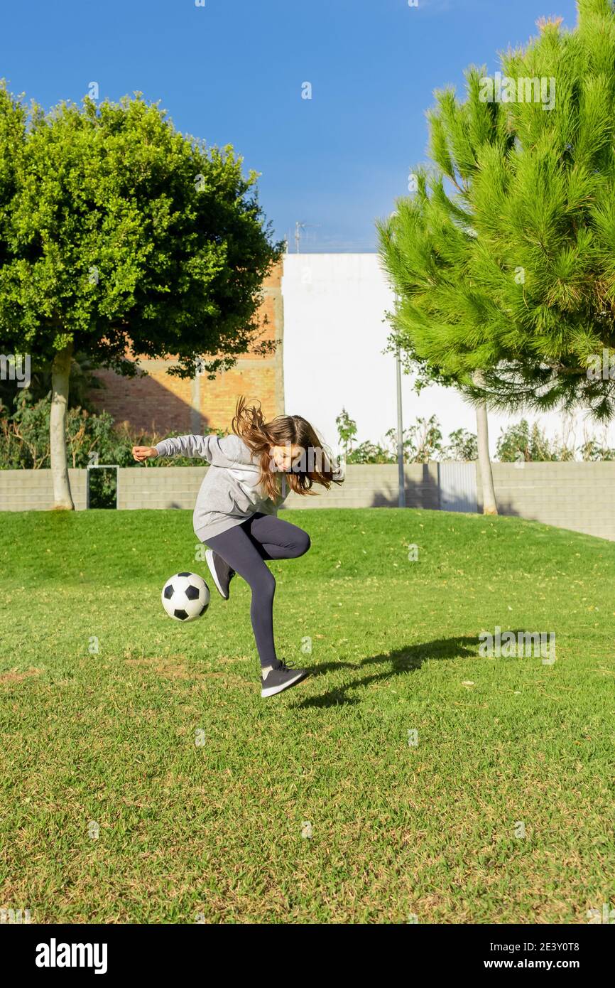 Beautiful little girl playing soccer in a nice park with natural grass ...