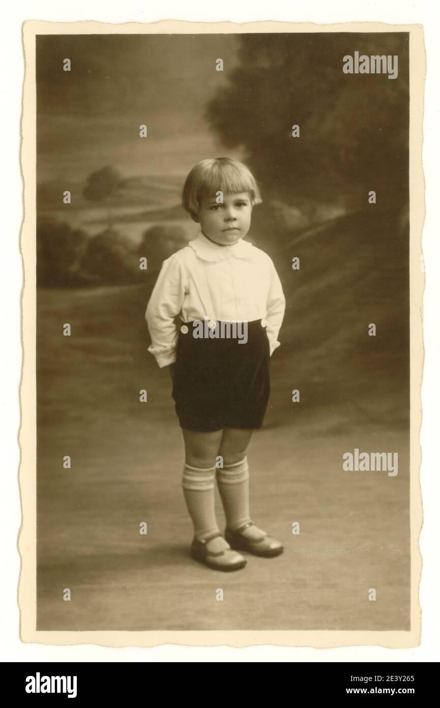 Original early 1900's studio portrait photo of boy aged about 3 years with bob hairstyle, standing looking serious, U.K. circa 1925 Stock Photo