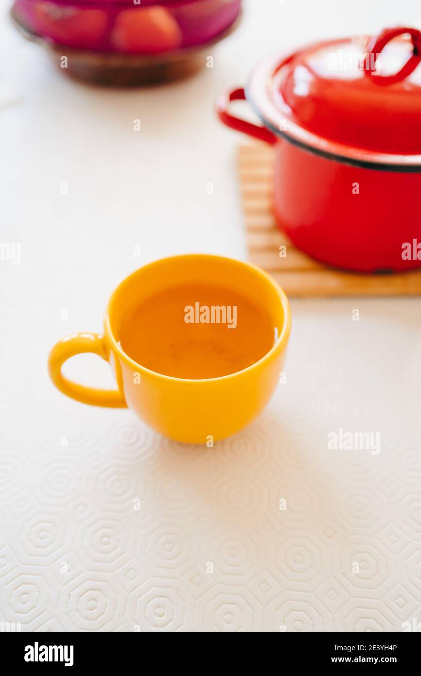 Yellow cup with a hot drink on a white table Stock Photo