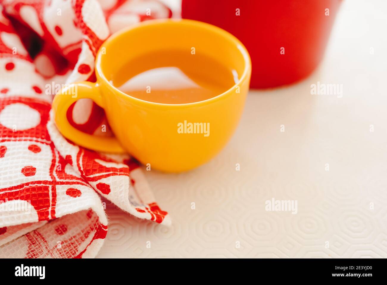 Yellow cup with a hot drink on a white table Stock Photo