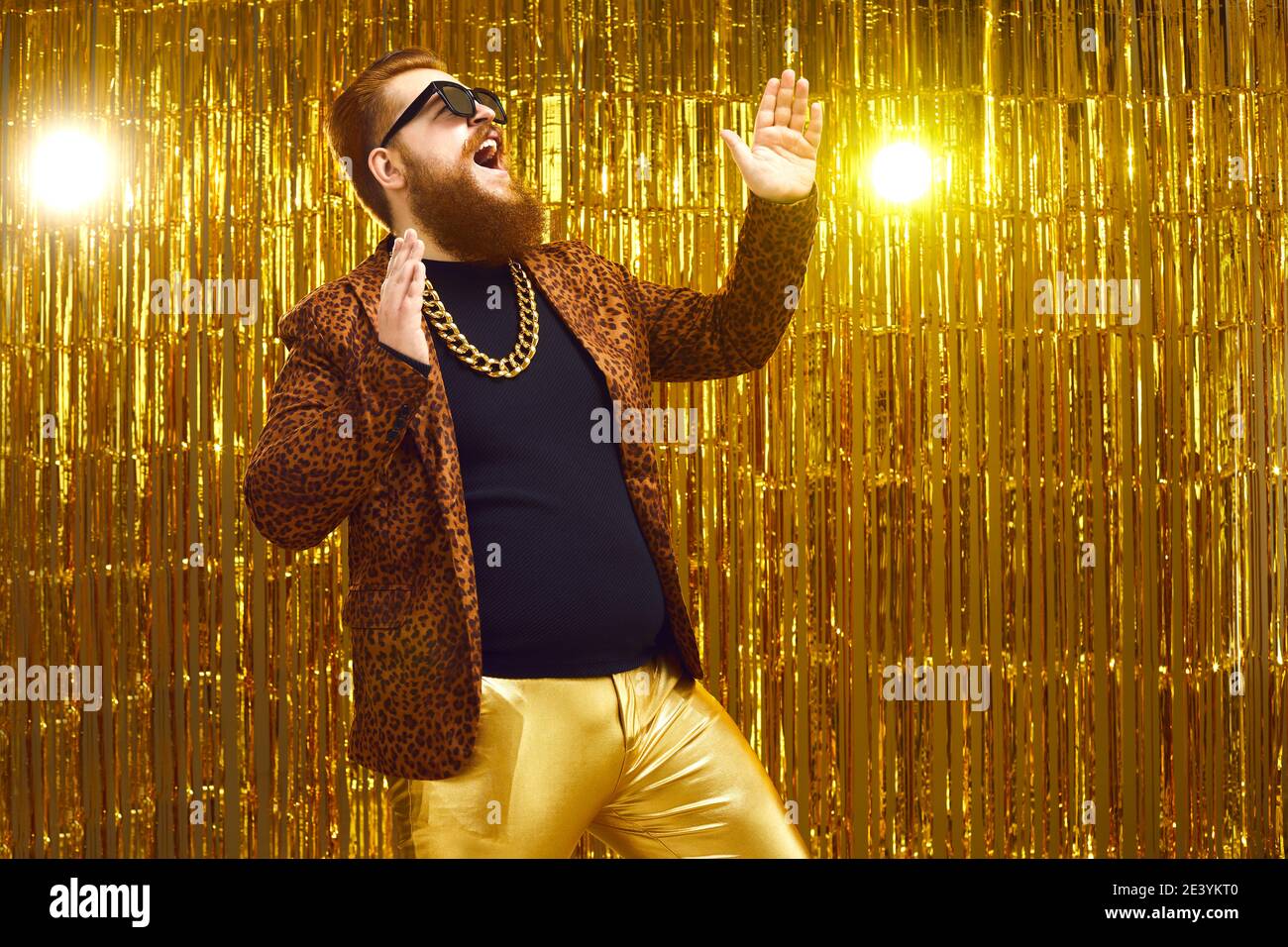 Happy bearded showman singing, dancing and having fun on stage with golden background Stock Photo