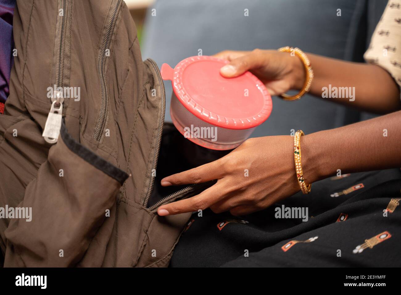 Close up shot of mother hands placing tiffin and water bottle box inside kids schools bag - concept of mother making kid ready for school Stock Photo