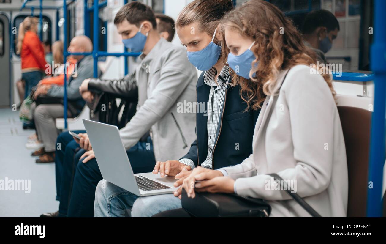subway passengers wearing protective masks using their laptops. Stock Photo
