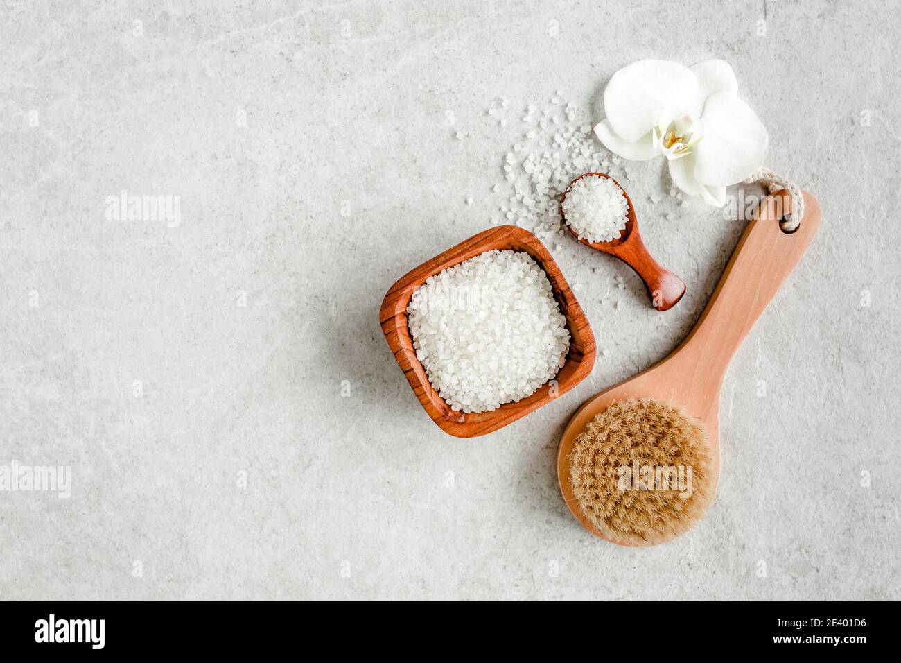 Spa skincare concept. Natural Organic spa cosmetics products, sea salt, massage brush and tropic palm leaves on gray marble table from above.  Stock Photo