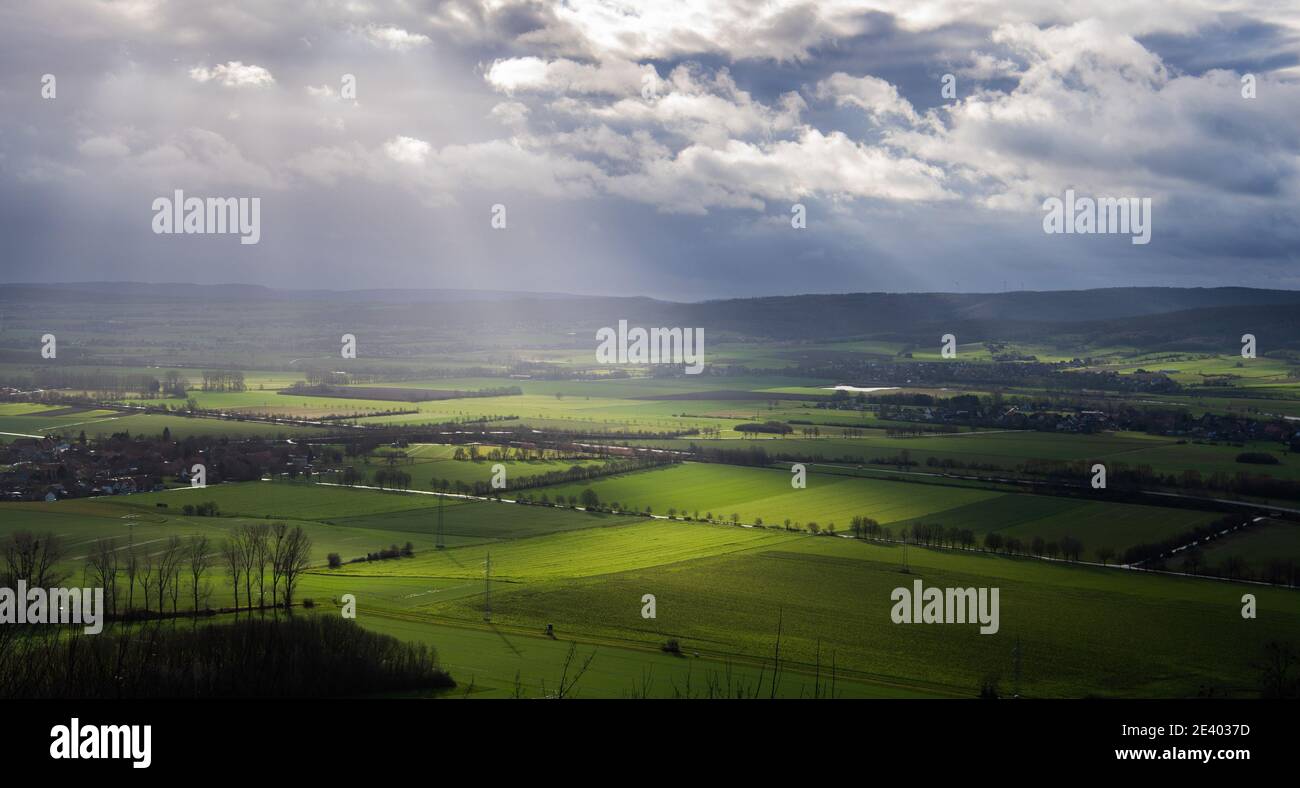 Hessisch Oldendorf, Germany. 21st Jan, 2021. Rays of sunshine between dark clouds hit fields in the district of Hameln-Pyrmont. Credit: Julian Stratenschulte/dpa/Alamy Live News Stock Photo