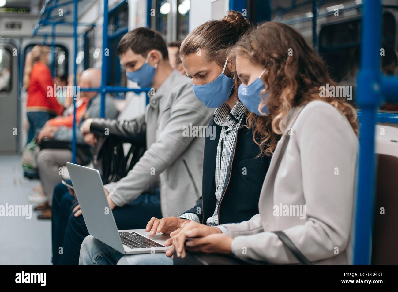 subway passengers wearing protective masks using their laptops. Stock Photo
