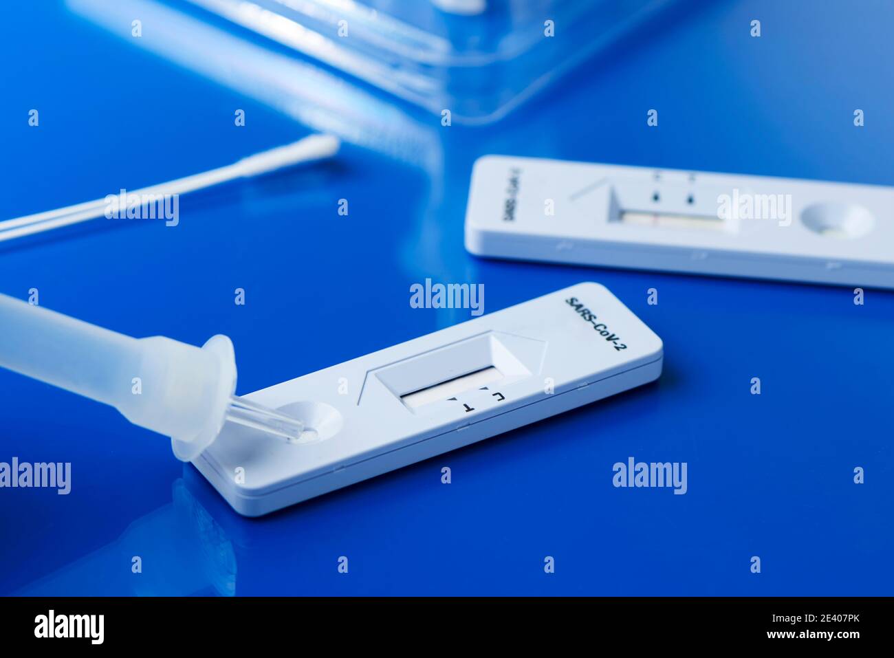some covid-19 rapid antigen test kits, with the diagnostic test devices and some nasopharyngeal swabs, on a blue surface Stock Photo