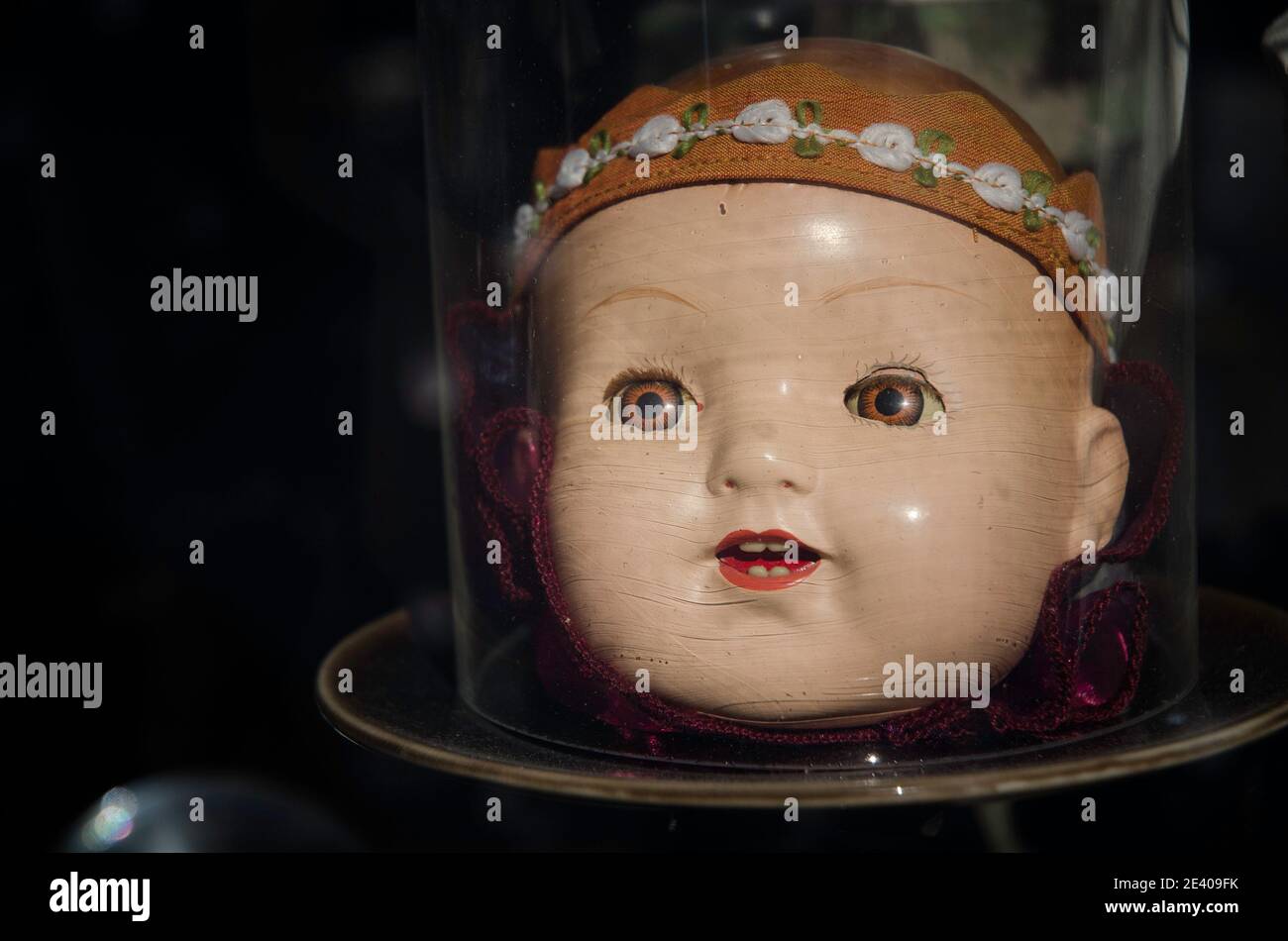 Close-up of an antique dolls head under a bell jar. Stock Photo