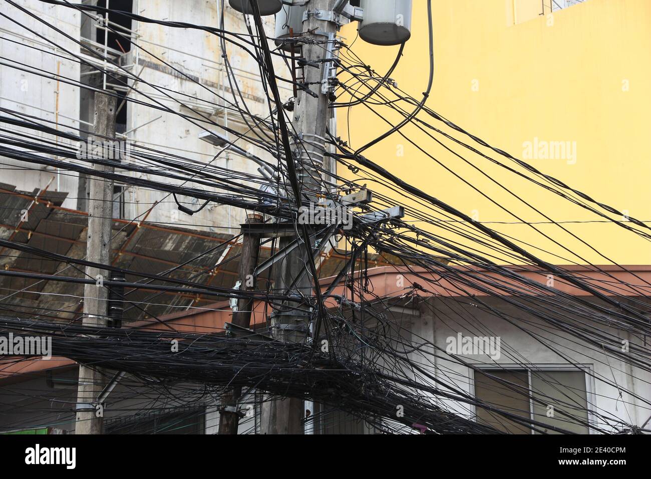 Messy cables and tangled wires - chaotic infrastructure of Manila, Philippines. Asian city cable chaos. Stock Photo