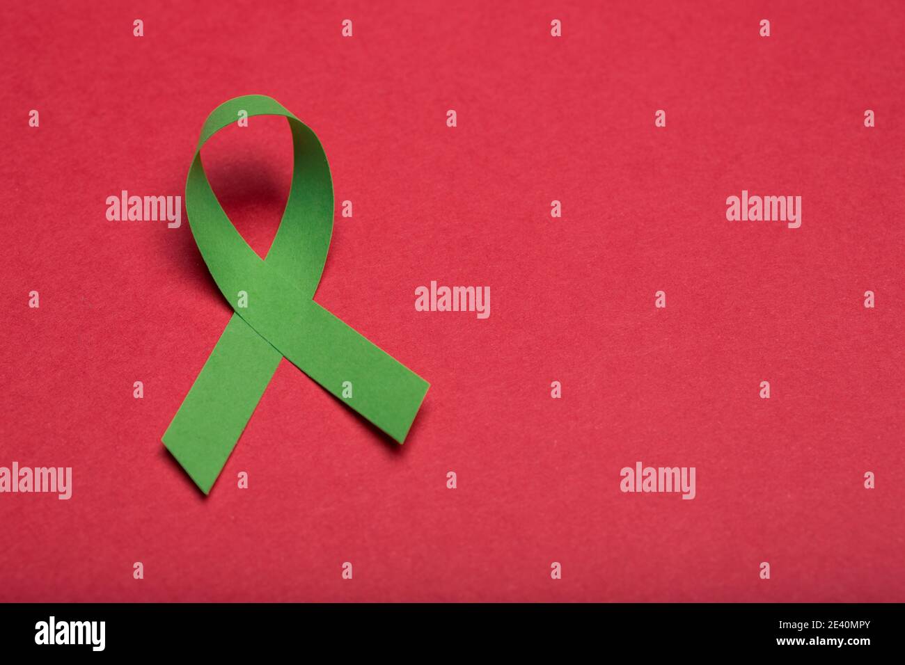 Green handmade awareness paper ribbon on white background. Stock Photo