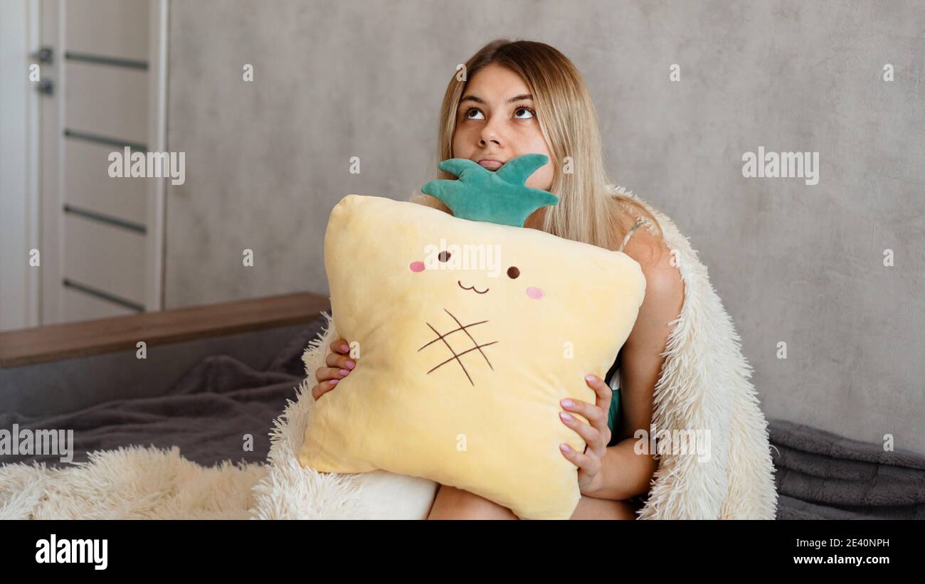 Young woman sitting on sofa and thinking. Beautiful girl holding