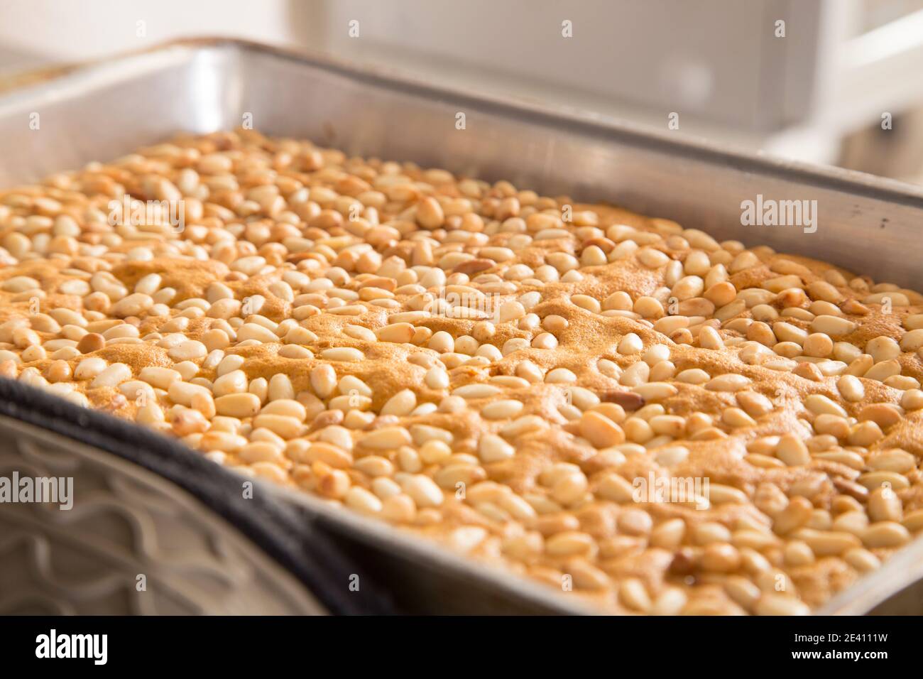 Ready sponge cake with pine nuts in a baking dish. Close-up. Stock Photo