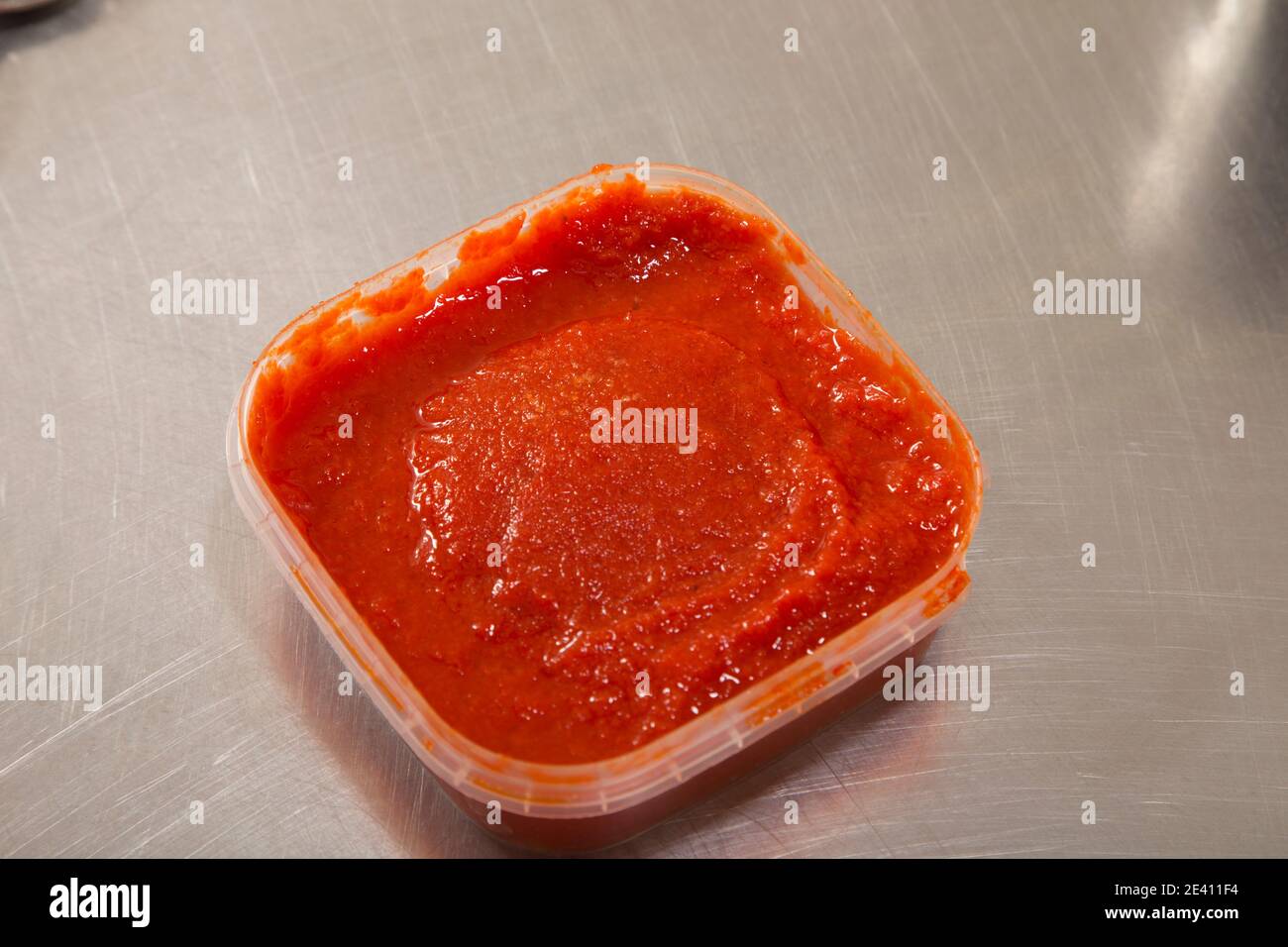 A red hot sauce made of roasted bell peppers. It is located on a metal surface. Close-up. Stock Photo
