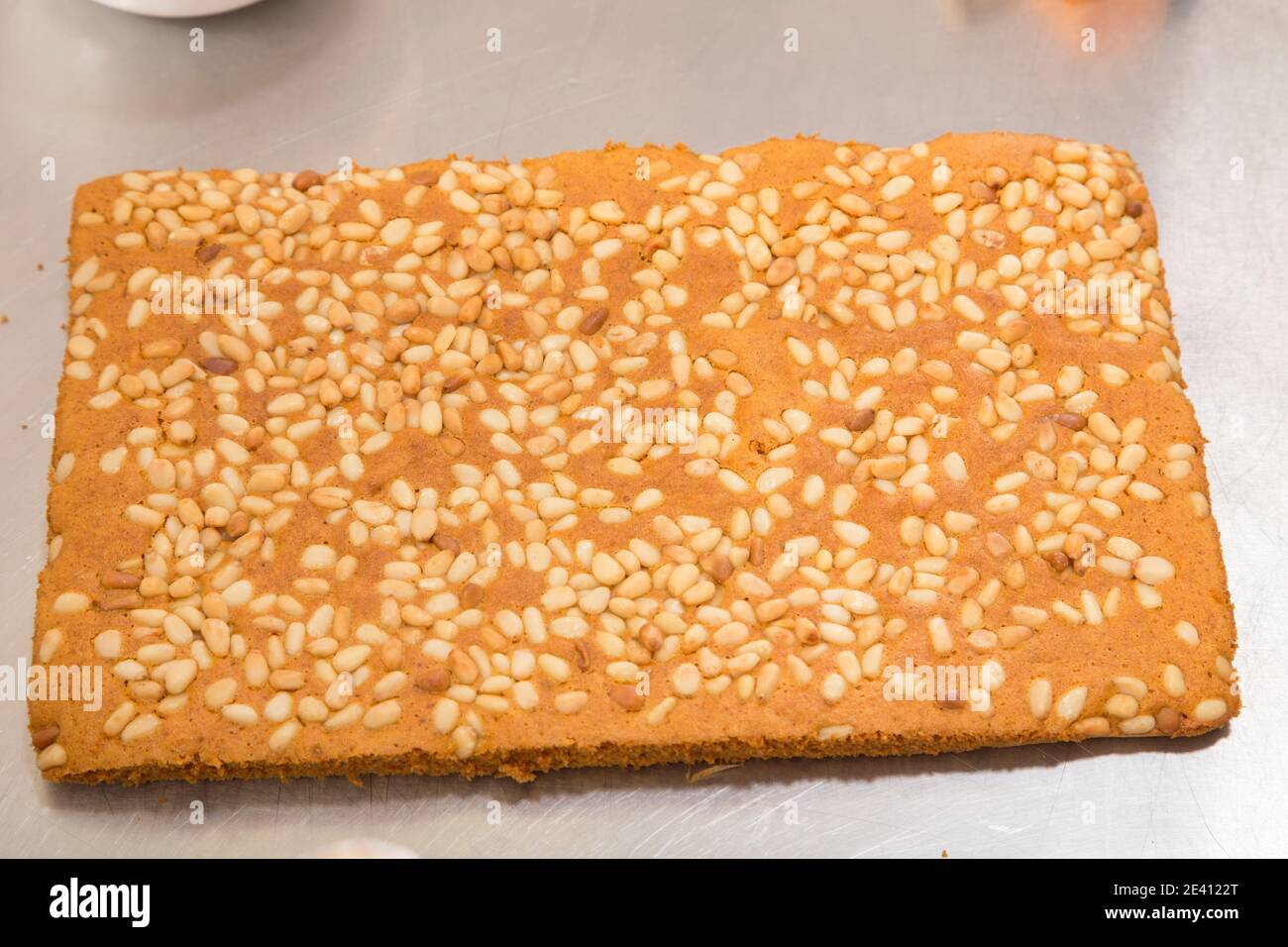 Ready carrot sponge cake with pine nuts. It is located on a metal surface. Close-up. Stock Photo
