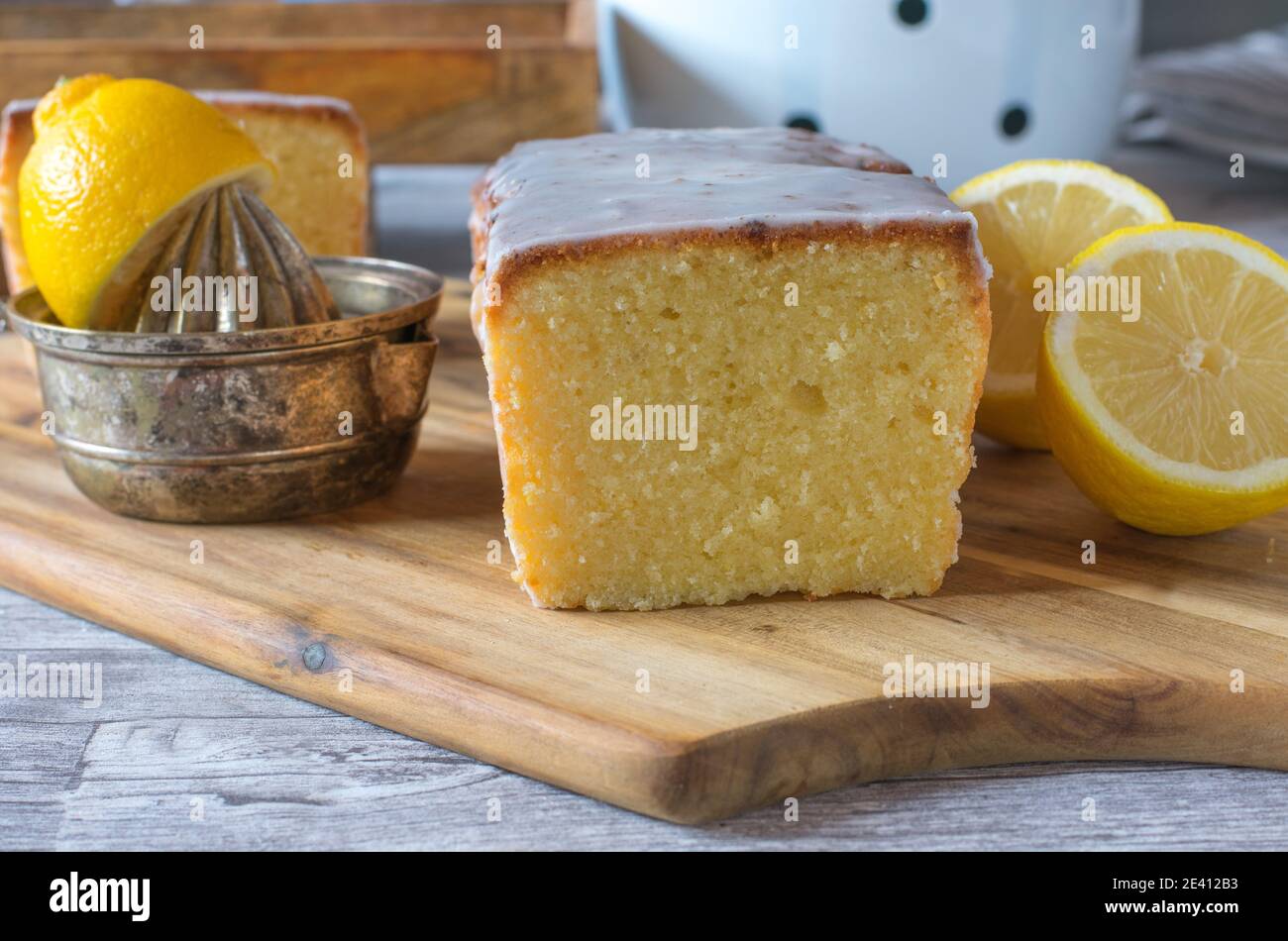 Delicious lemon cake with frosting on wooden board with rustic kitchen utensils Stock Photo