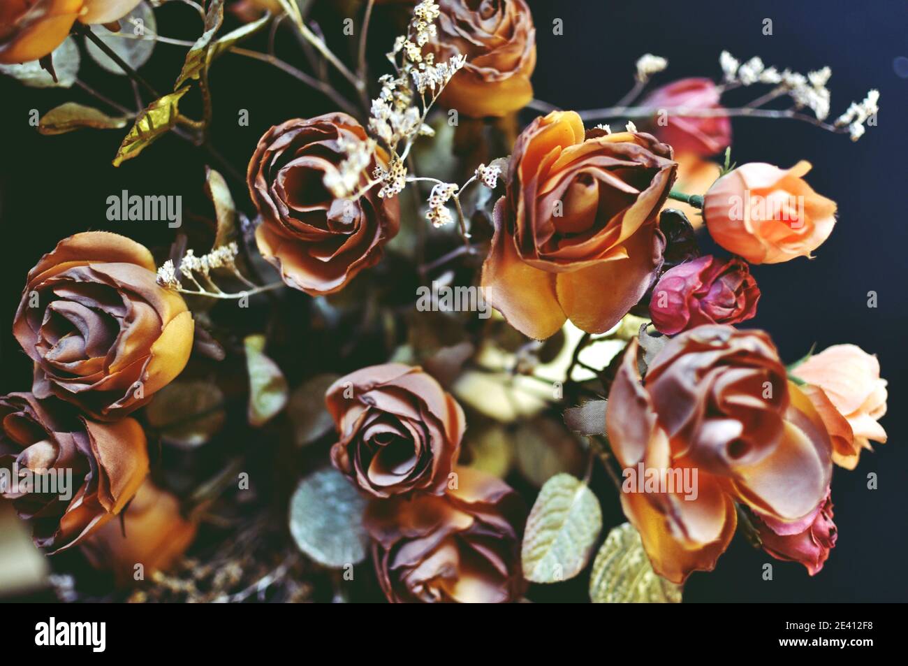 A top view close up of autumn brown colored artificial roses on black ...
