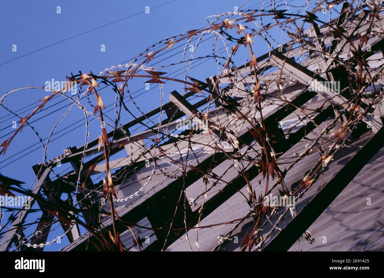Detail of razor wire (some rusted) and barbed wire on bridge over river ...