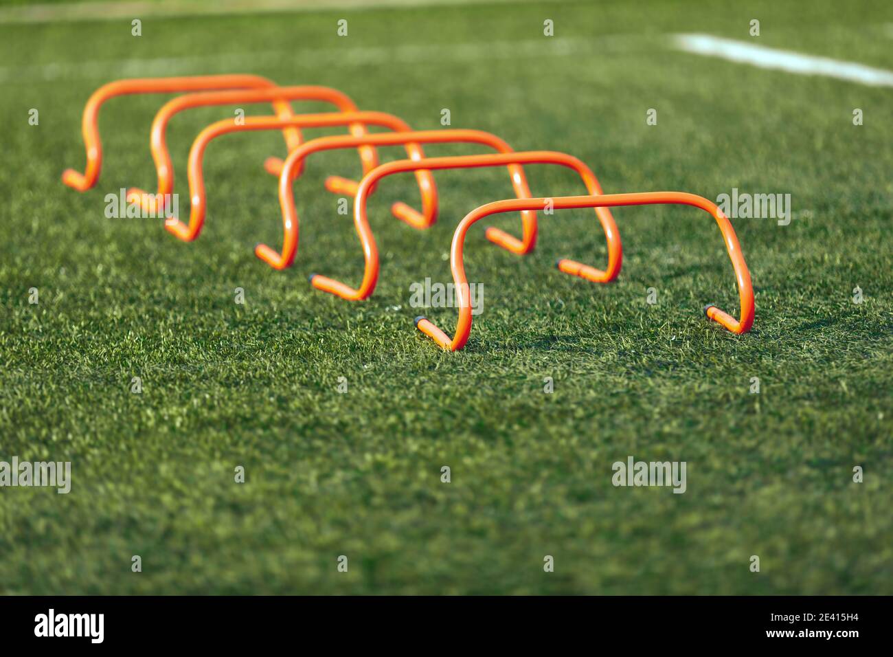 Set of soccer hurdles. Orange football hurdles training. Grass practice field Stock Photo
