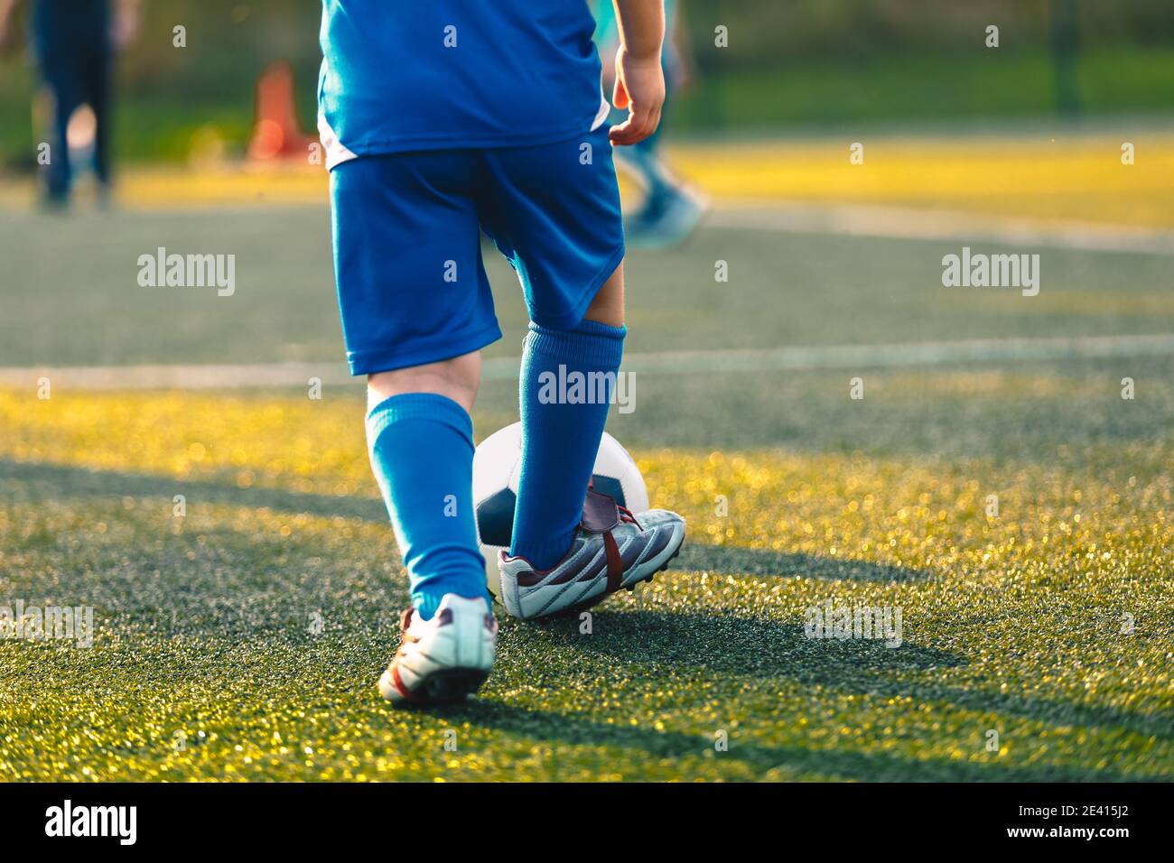 Child playing sports. Kids playing football ball on grass pitch. Soccer training on summer sunny day Stock Photo