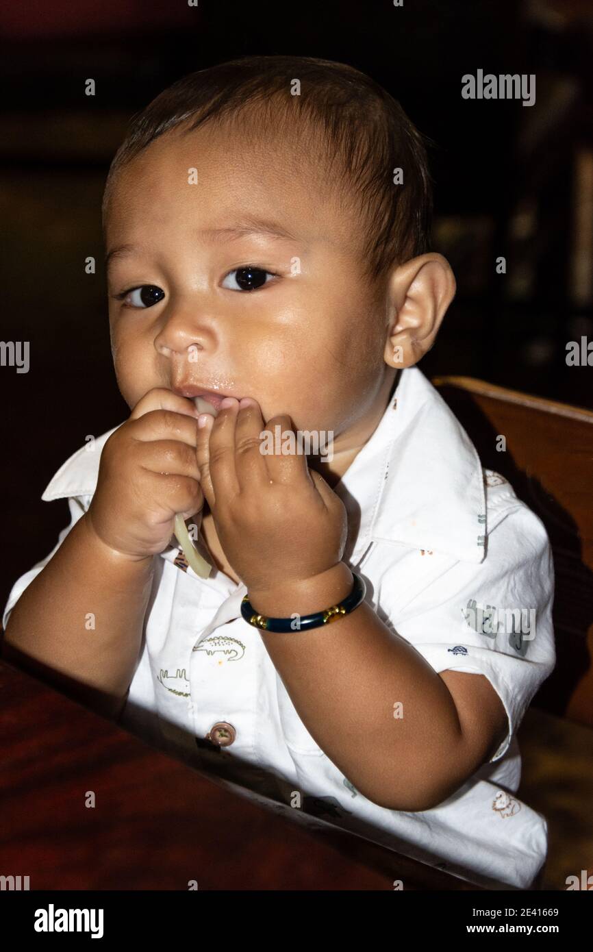 Adorable Filipino American baby eating noodles by hand Stock Photo Alamy