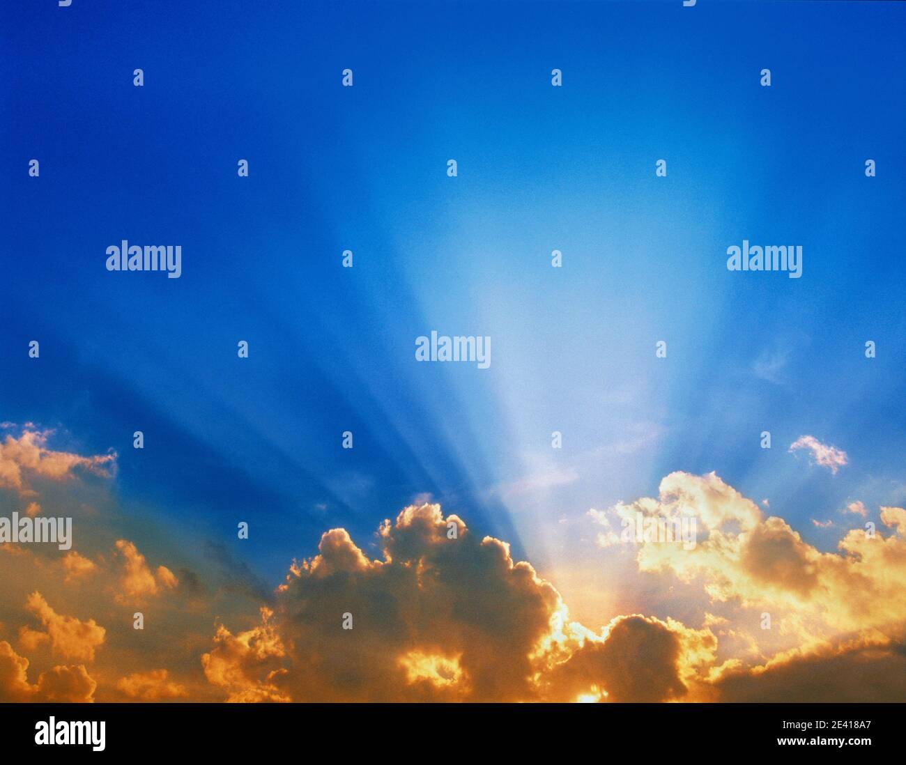 Sun Rays suns ray shafts of light through clouds with bright blue sky above religious biblical skies Stock Photo