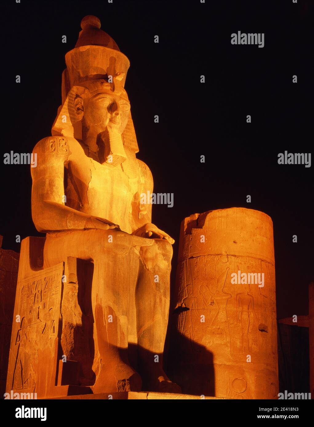 North Africa Egypt Luxor temple statue of Ramesses II illuminated lit up at night nightime with dark sky vertical Stock Photo