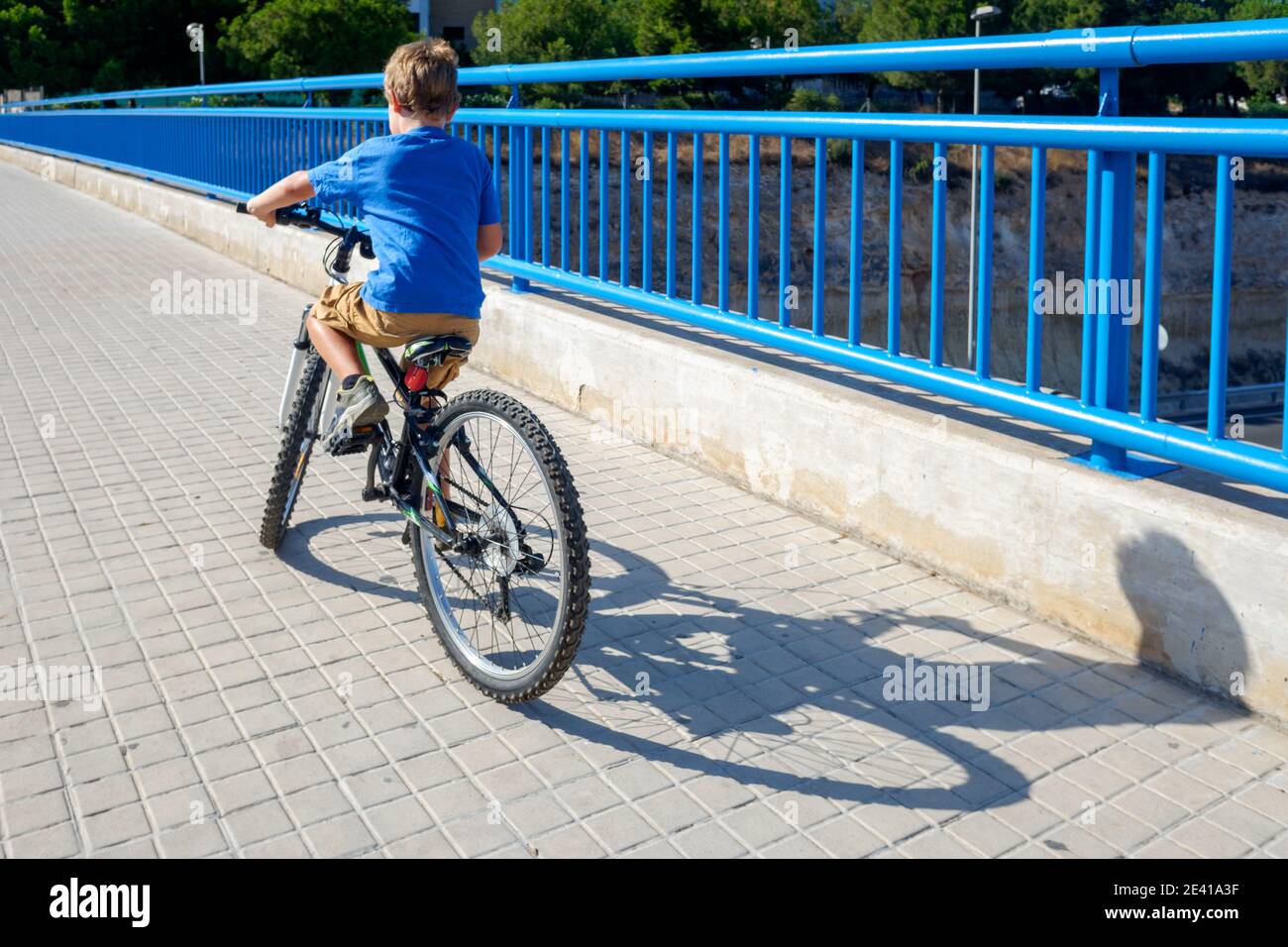 Boy in blue t-shirt learning to ride a bike on a summer day. Stock Photo