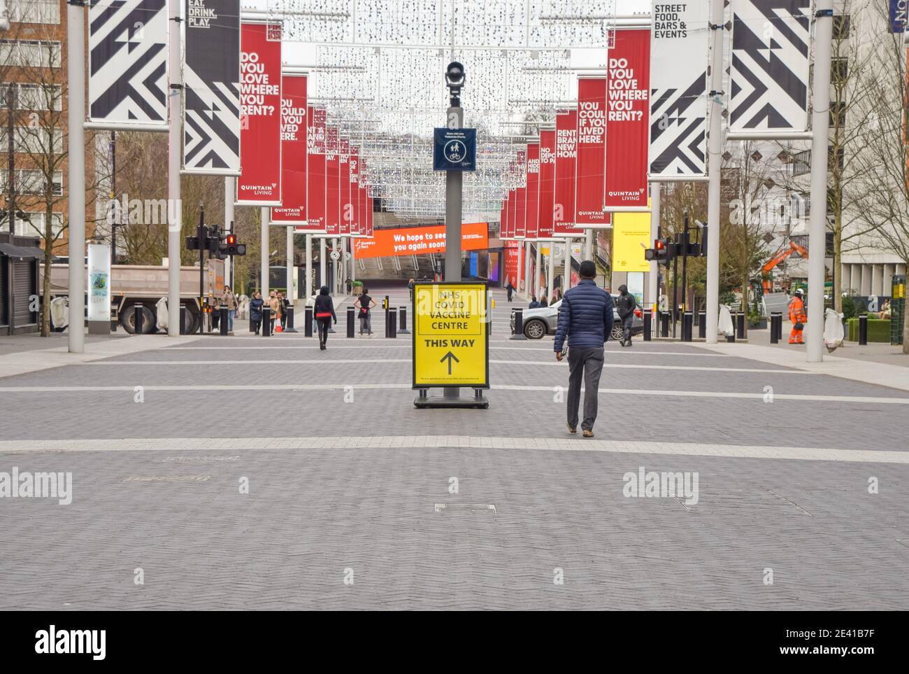 London, UK. 21st Jan, 2021. A man walks past a sign for the NHS covid-19 Vaccine Centre in Wembley.Several mass vaccination sites have been opened around England, as the government rolls out its coronavirus vaccination program. Credit: SOPA Images Limited/Alamy Live News Stock Photo