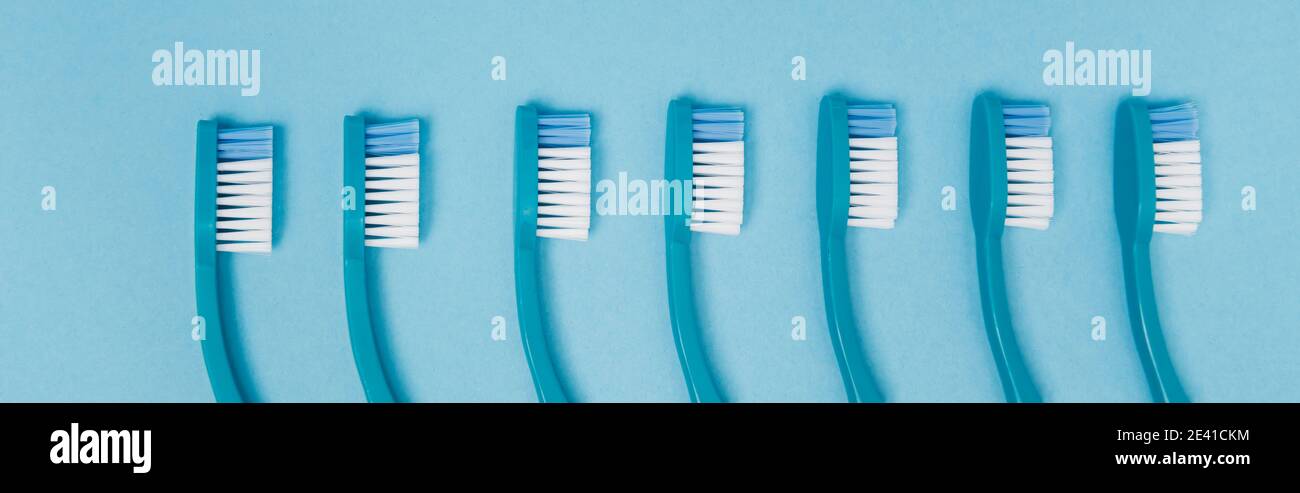 Top view of row of toothbrushes on blue background, banner Stock Photo ...