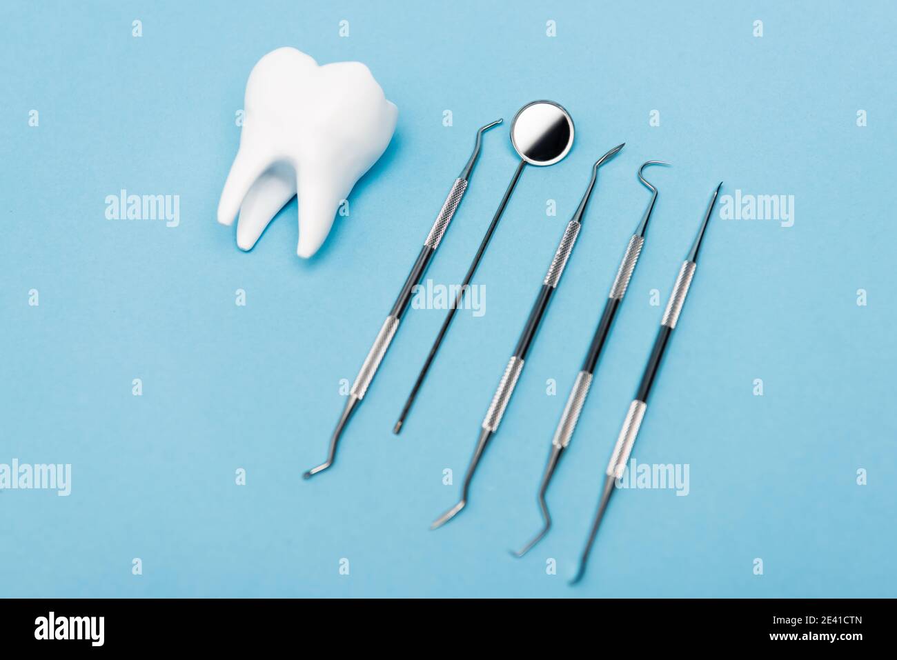 White tooth model and dental tools on blue background Stock Photo - Alamy