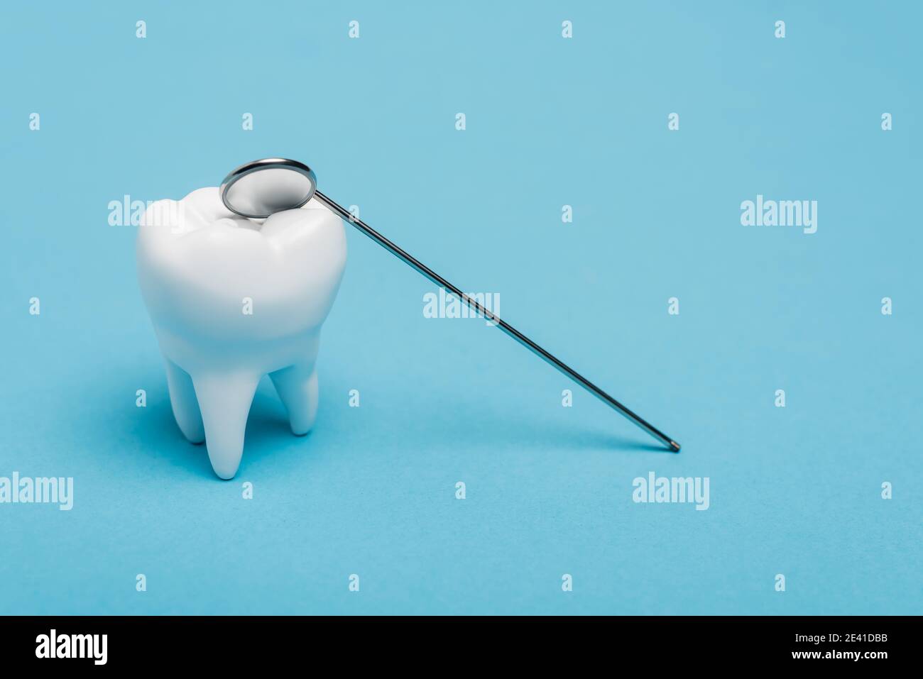 Tooth model and dental mirror on blue background Stock Photo - Alamy
