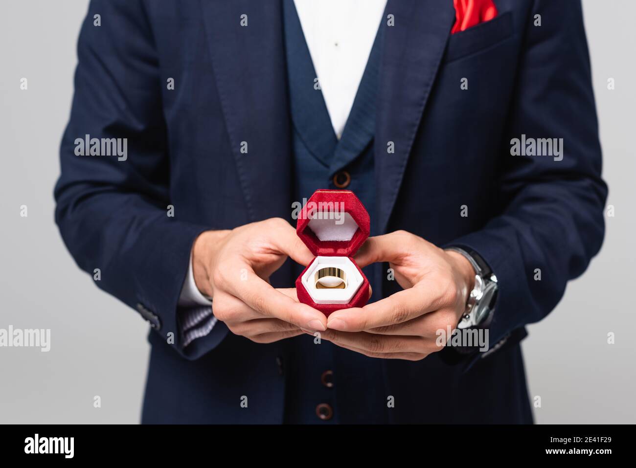 cropped view of elegant man holding jewelry box with wedding ring isolated on grey Stock Photo