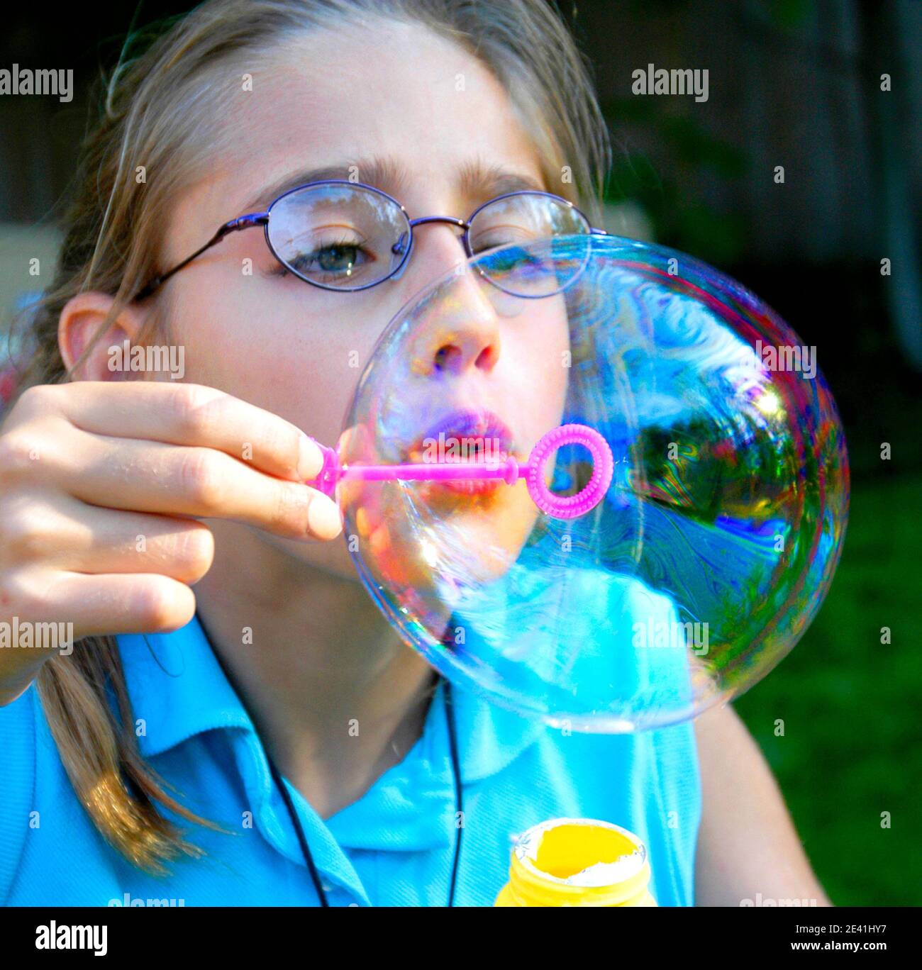 Girl blowing large soap bubbles from a bubble wand Stock Photo Alamy