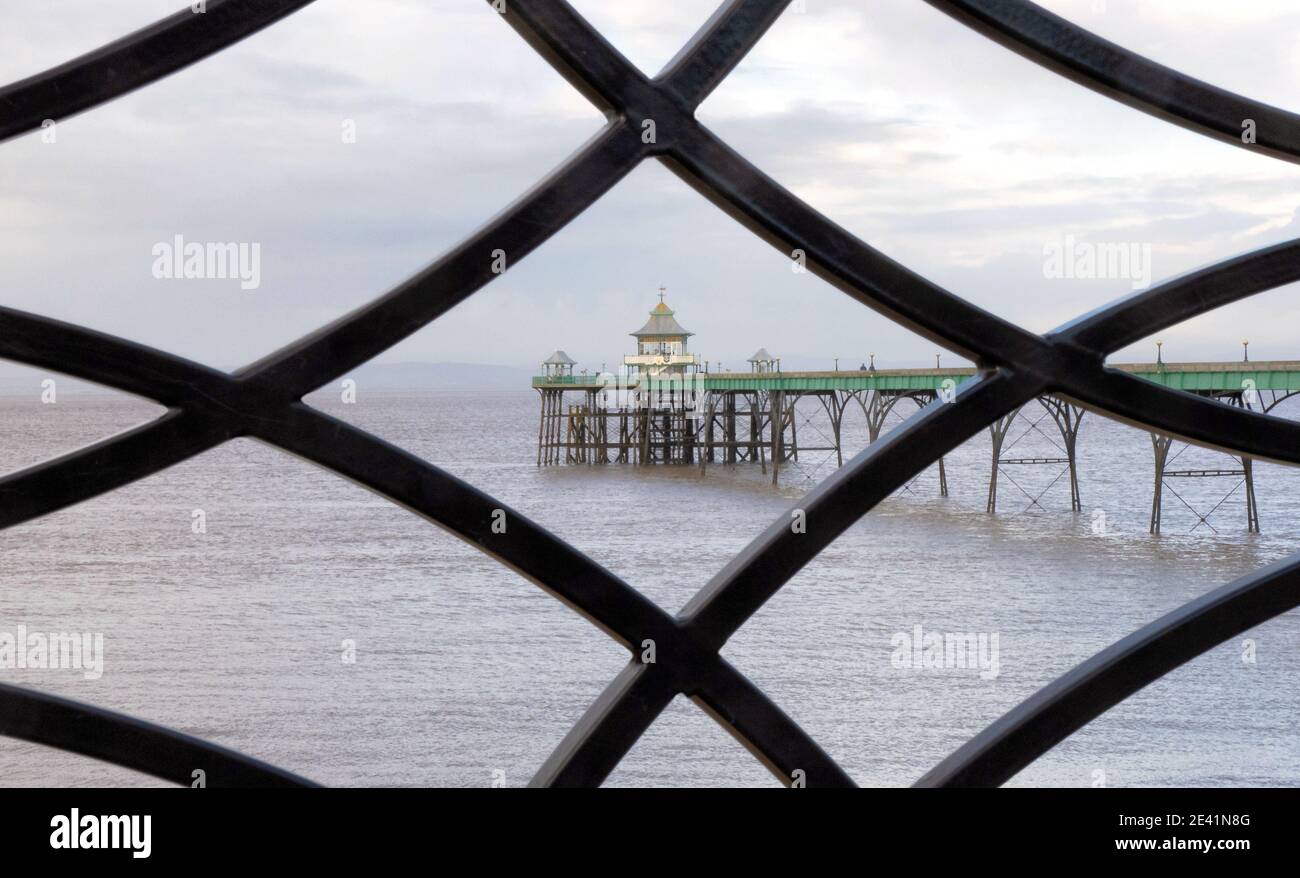 Clevedon Pier framed through the wrought iron ballustrade of the sea front promenade - Somerset UK Stock Photo