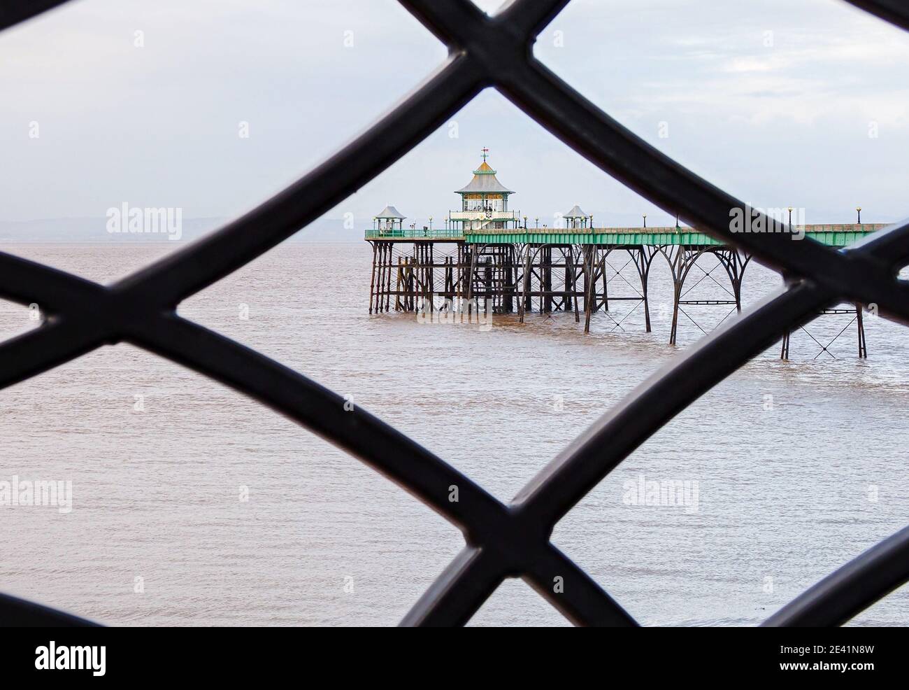 Clevedon Pier framed through the wrought iron ballustrade of the sea front promenade - Somerset UK Stock Photo