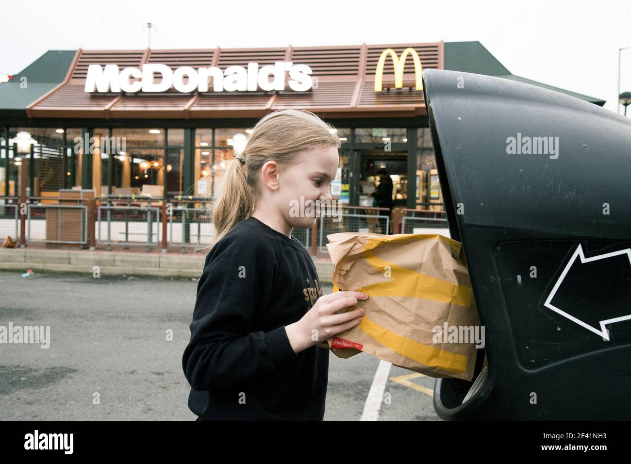 Mia West throws away McDonalds takeaway bags outside their restaurant,  which is still open for drive thru customers only, in Beckton, London,  during England's third national lockdown to curb the spread of
