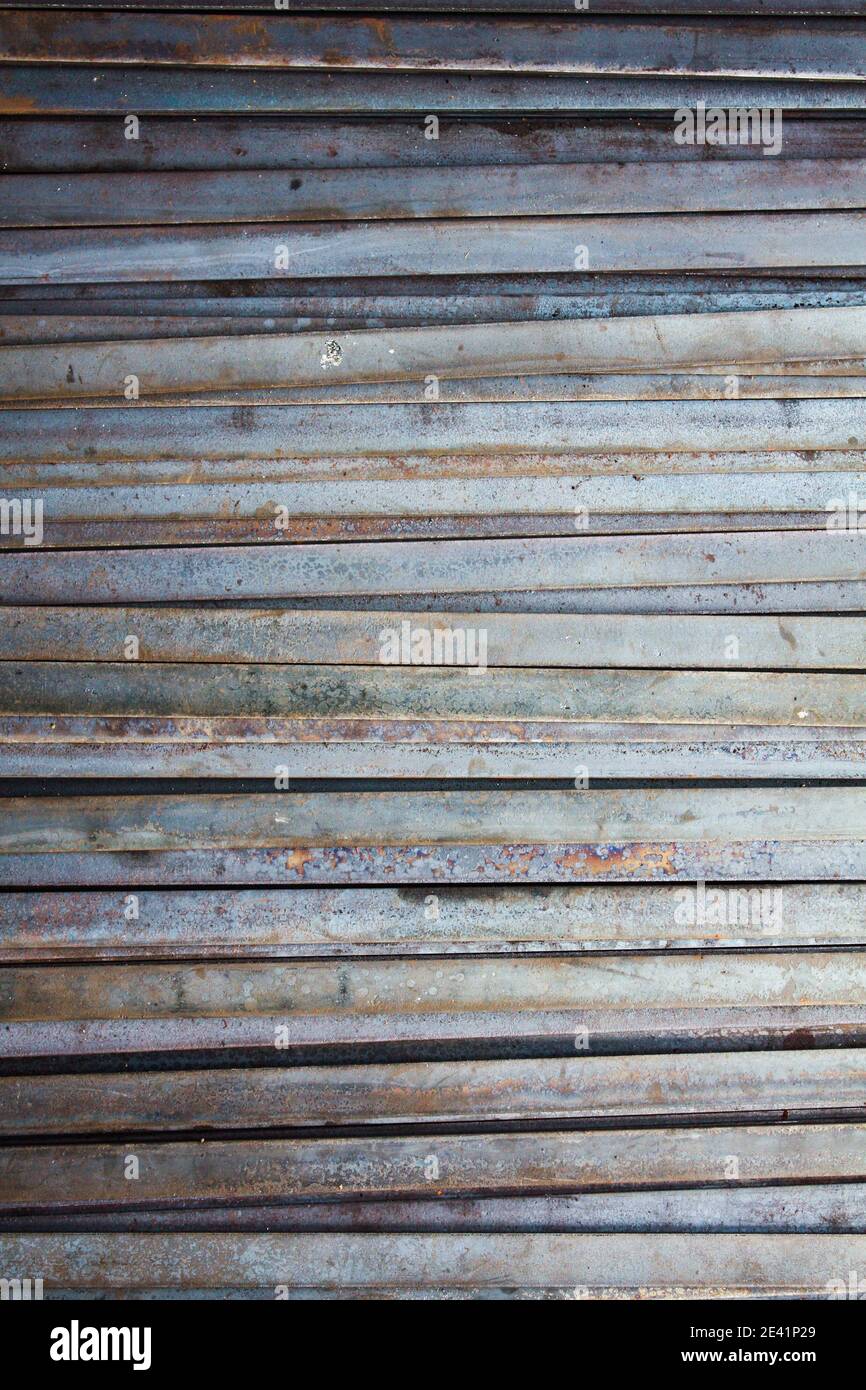 line pattern from metal flat bars tinted blue and rusted Stock Photo