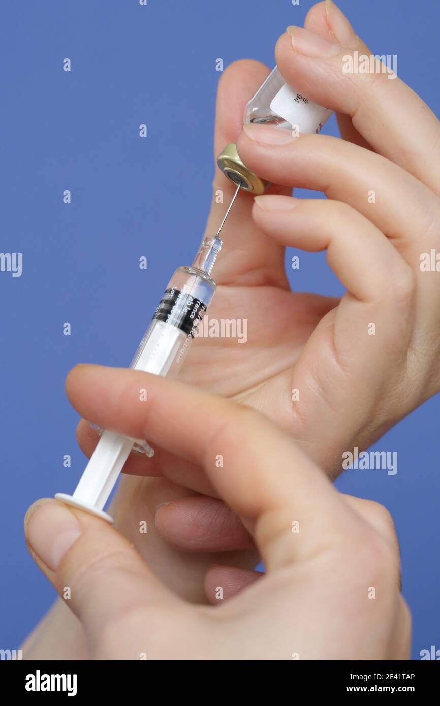 Healthcare concept: Hands of a young nurse in close-up holding a syringe and a dosing bottle, preparing an injection to vaccinate against diseases and Stock Photo