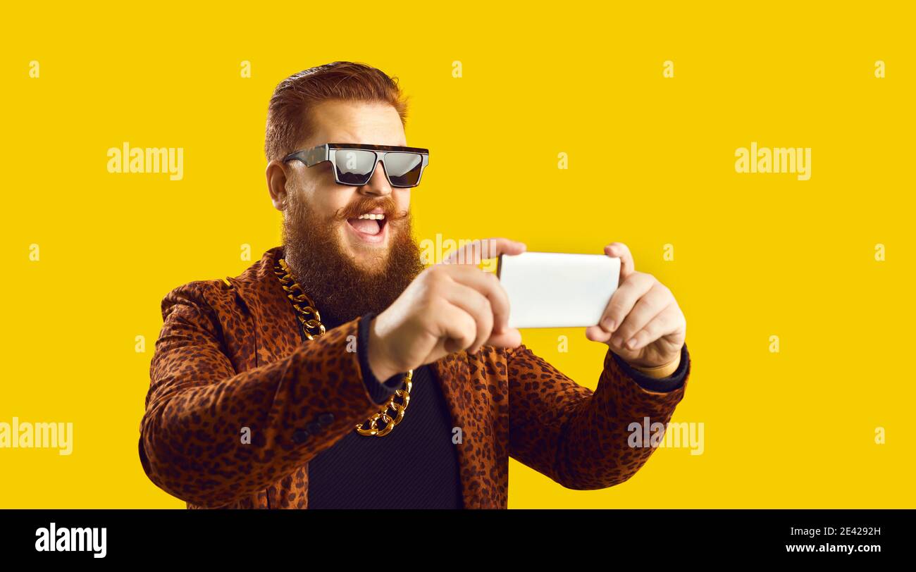 Happy man in extravagant outfit live streaming, recording video or taking selfie on mobile Stock Photo