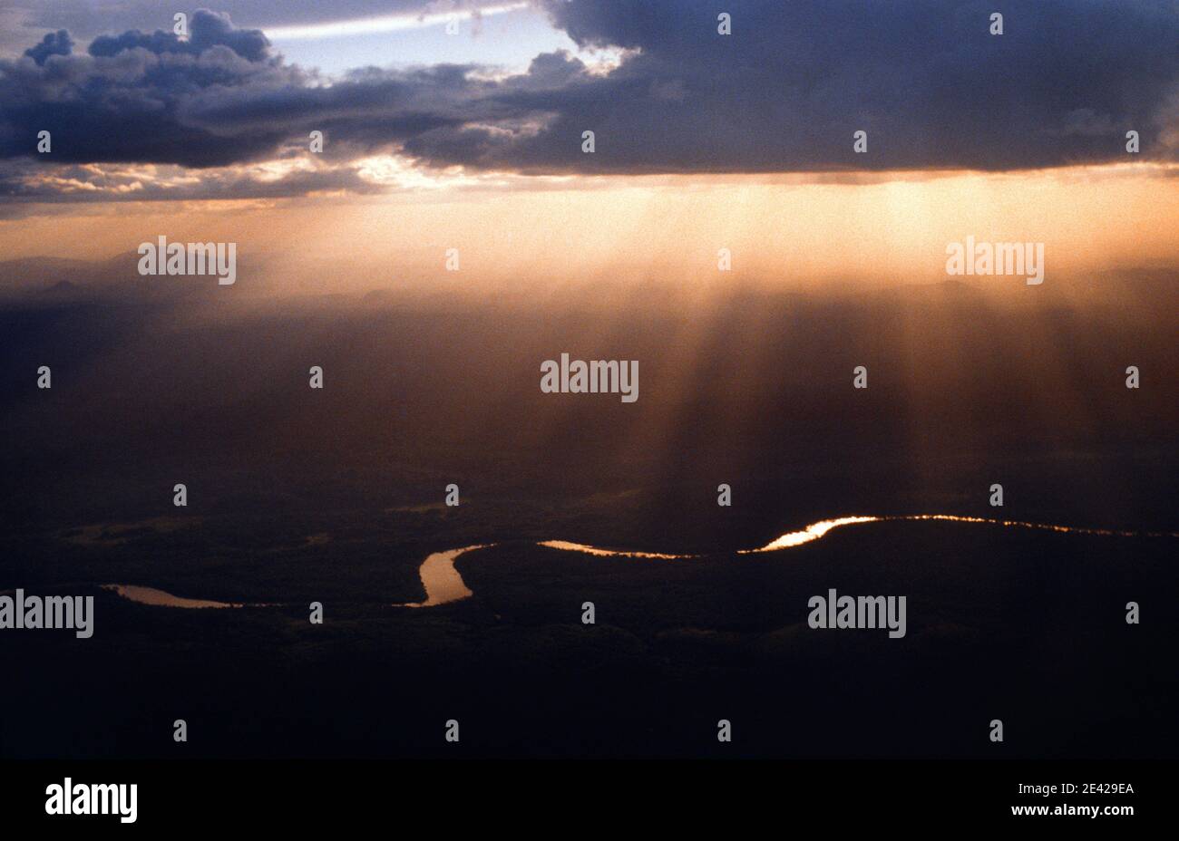 Aerial view of sinuous river in Amazon rain forest, solar rays through clouds at susnset, Brazil. Stock Photo