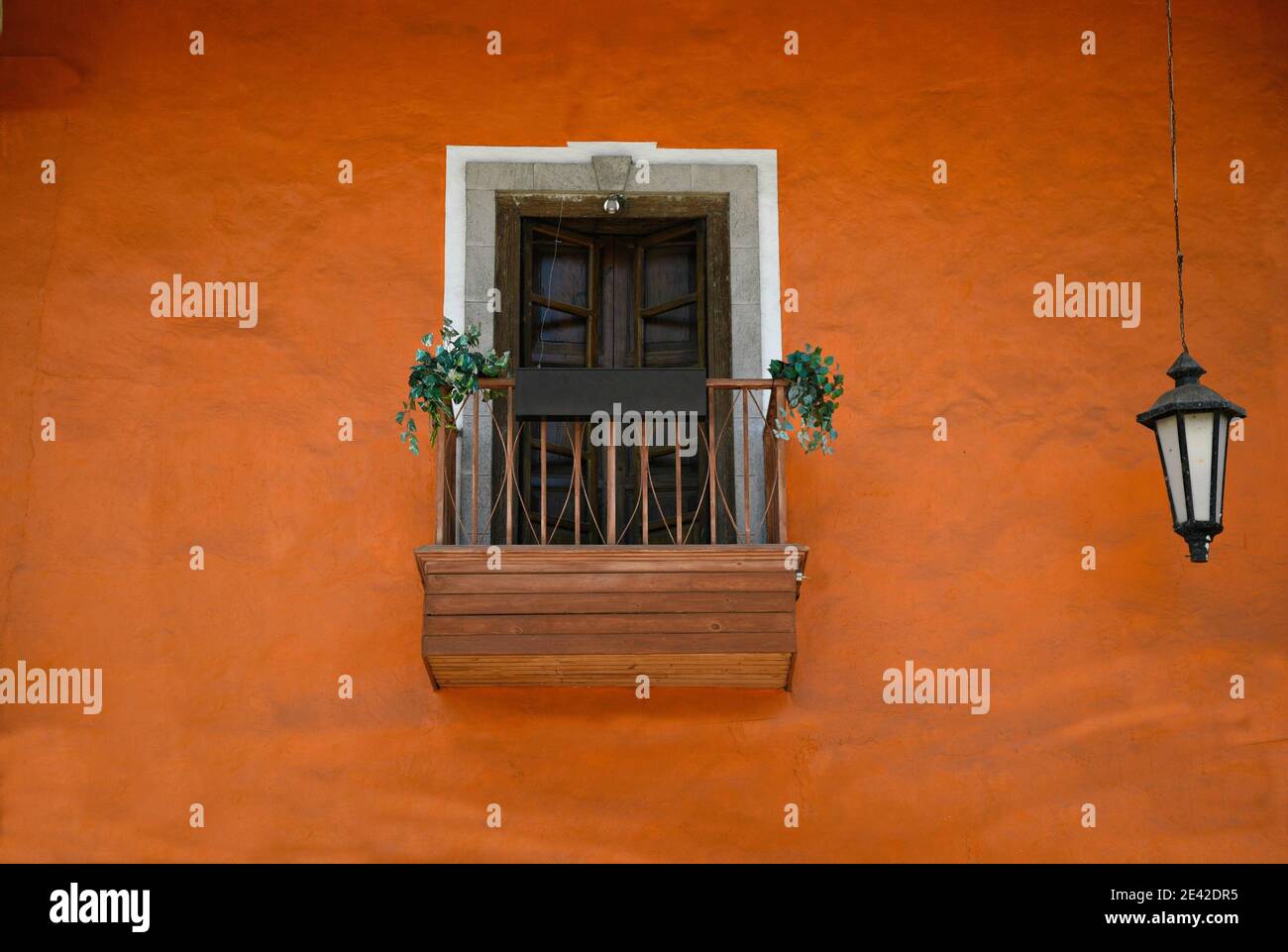 Colonial style facade with a Terracotta stucco wall a wooden window ...