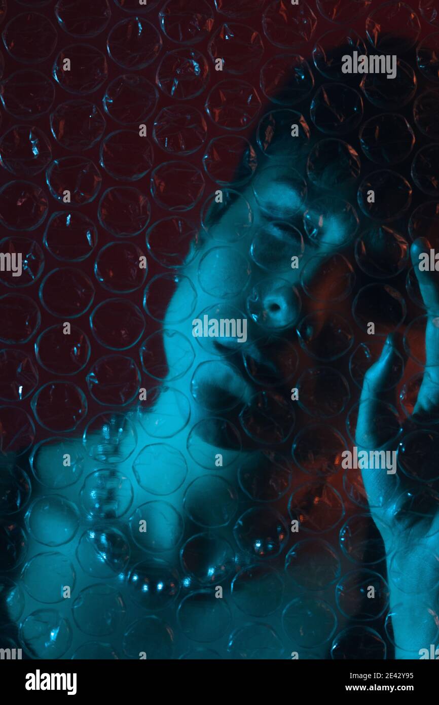 Creative portrait of a woman behind plastic bubble wrap with her eyes