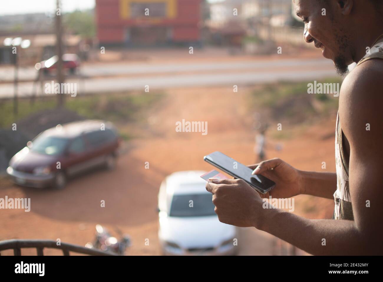 african man using his phone and a credit card Stock Photo