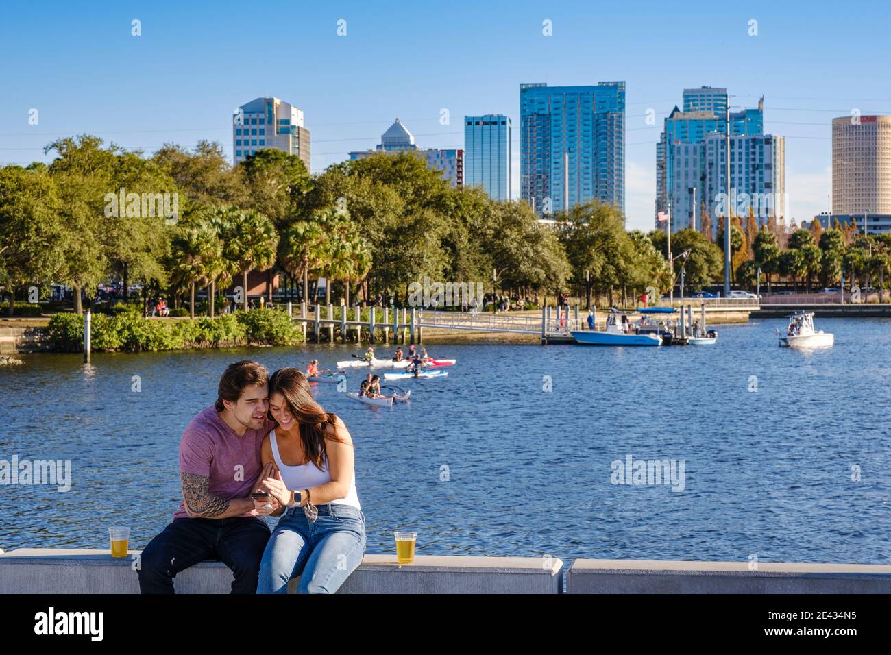 Couple enjoying a moment on their smartphone at the Tampa Riverwalk near Tampa Heights, Tampa, Florida. Tampa's first suburb established in 1883. Stock Photo