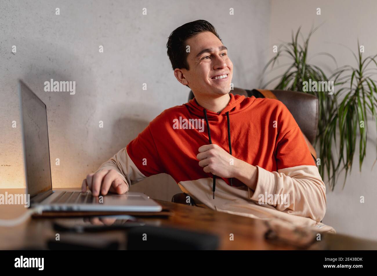 Young cheerful Hispanic male working on the computer and talking to ...